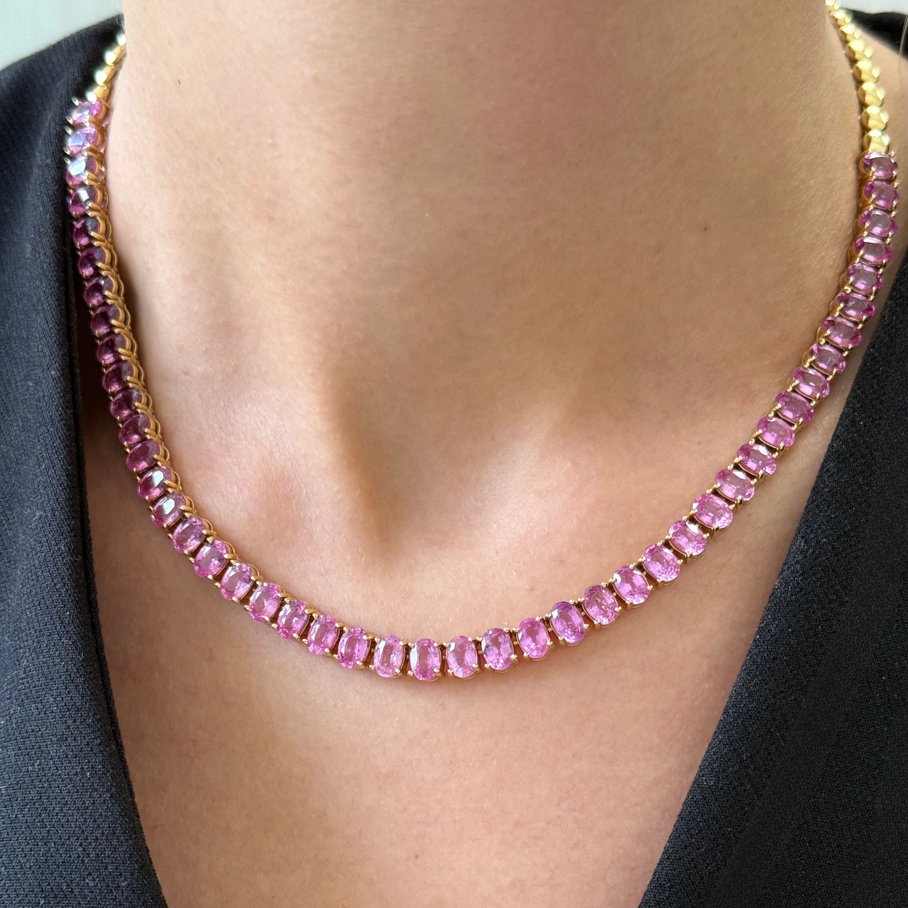 Necklace with pink gemstones worn by a person against a black background