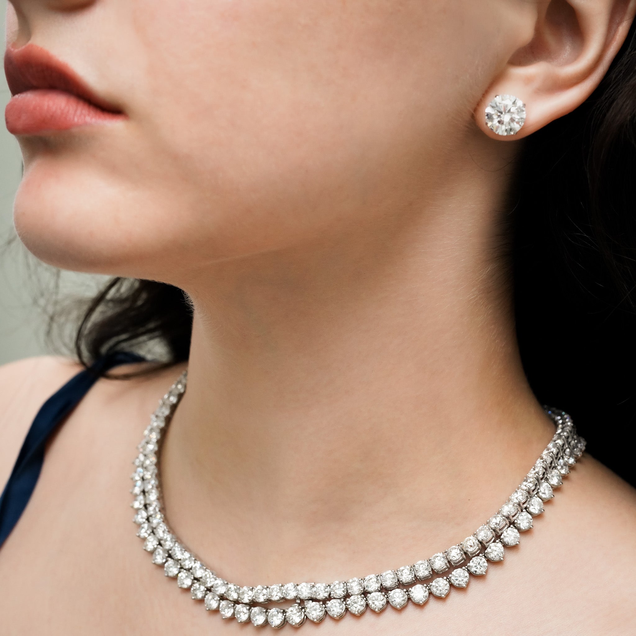 Close-up of a woman wearing a diamond necklace and earrings.