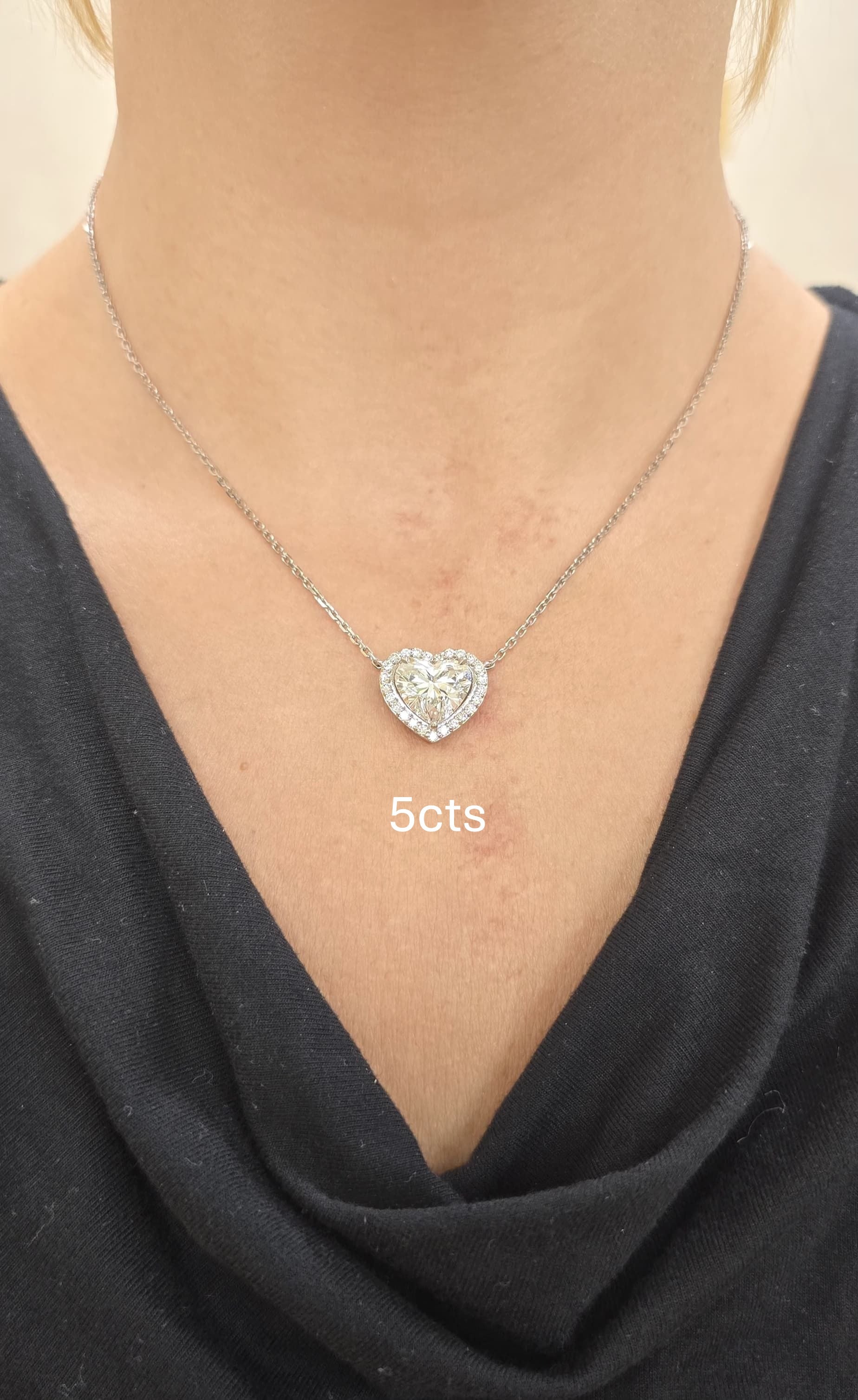 Heart-shaped diamond necklace on a person wearing a black top
