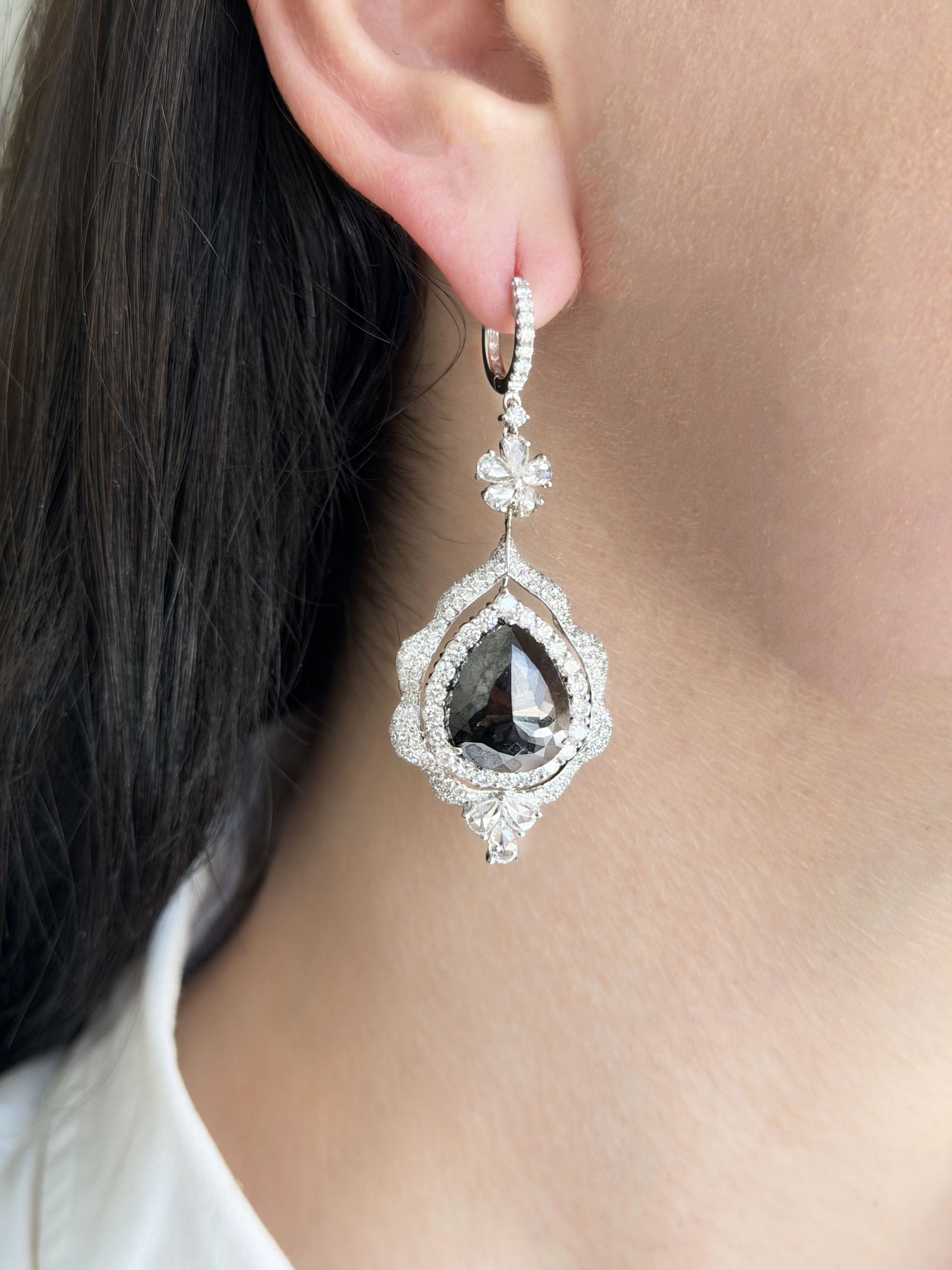 Close-up of a person wearing a sparkling earring with a dark gemstone.