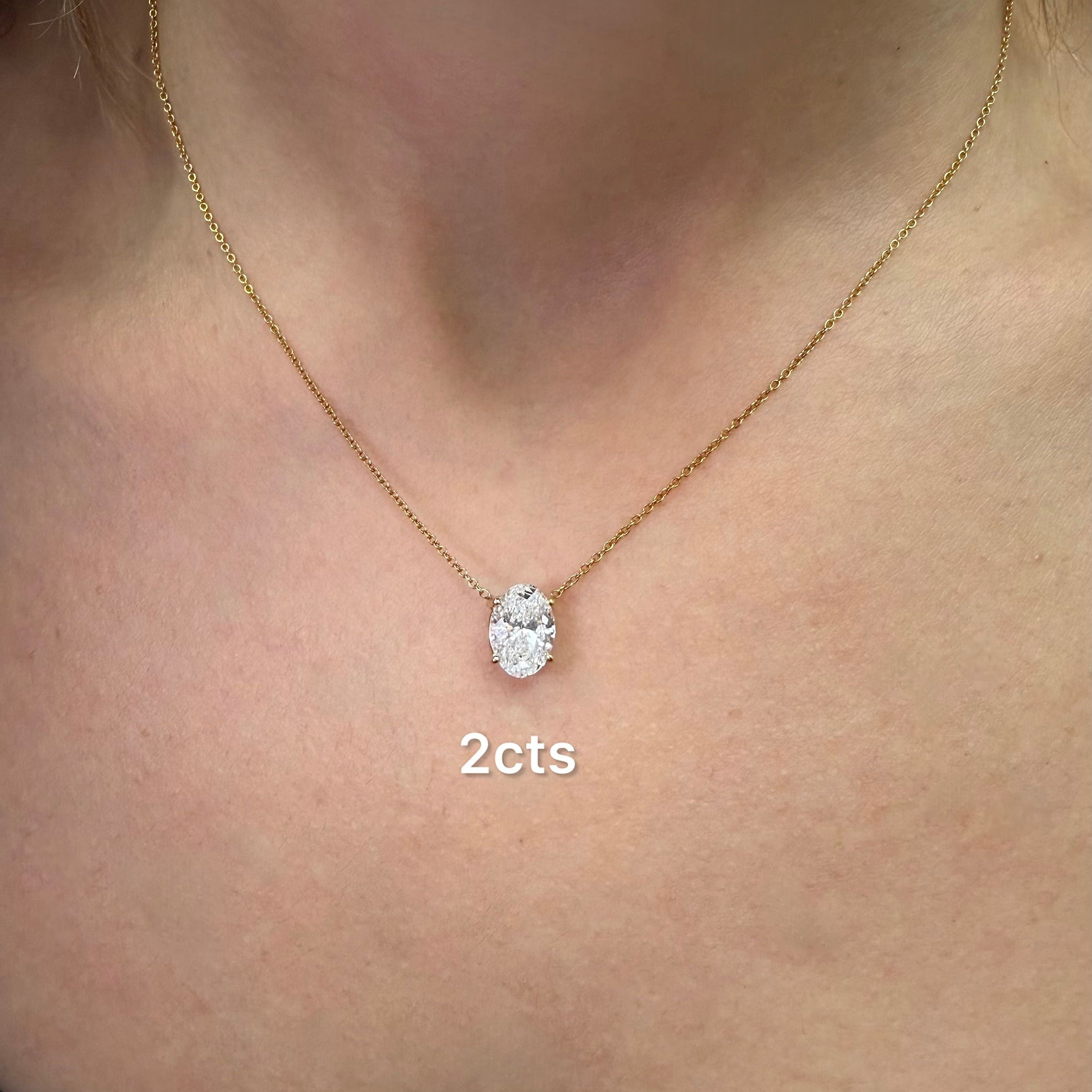 Gold necklace with a diamond pendant on a person's neck, labeled '2cts'.