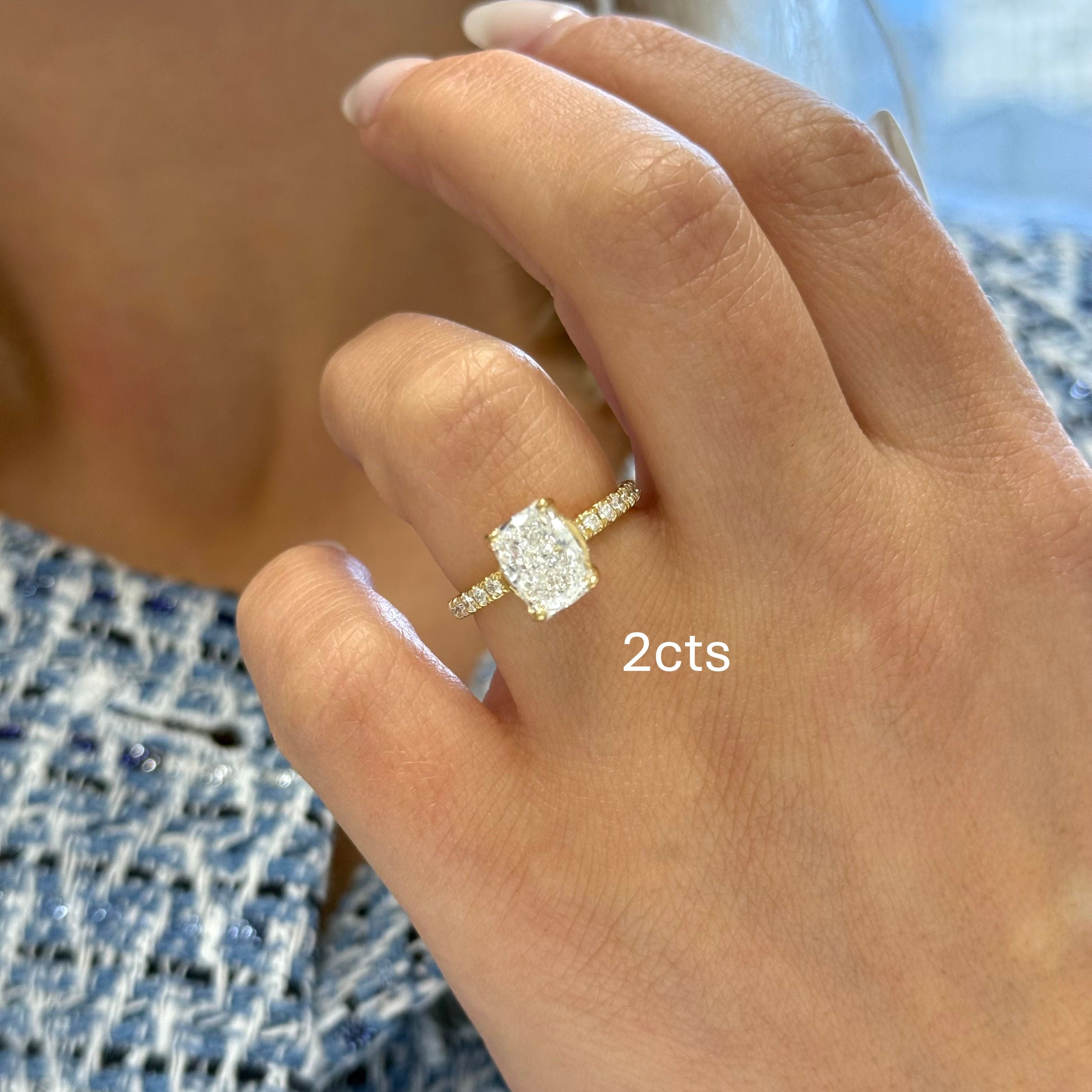 Close-up of a hand wearing a diamond ring with '2 cts' text.