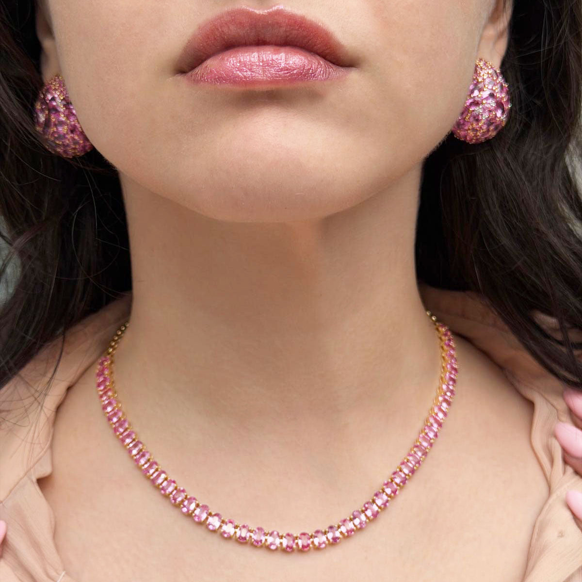 Close-up of a person wearing pink beaded jewelry with earrings and a necklace.