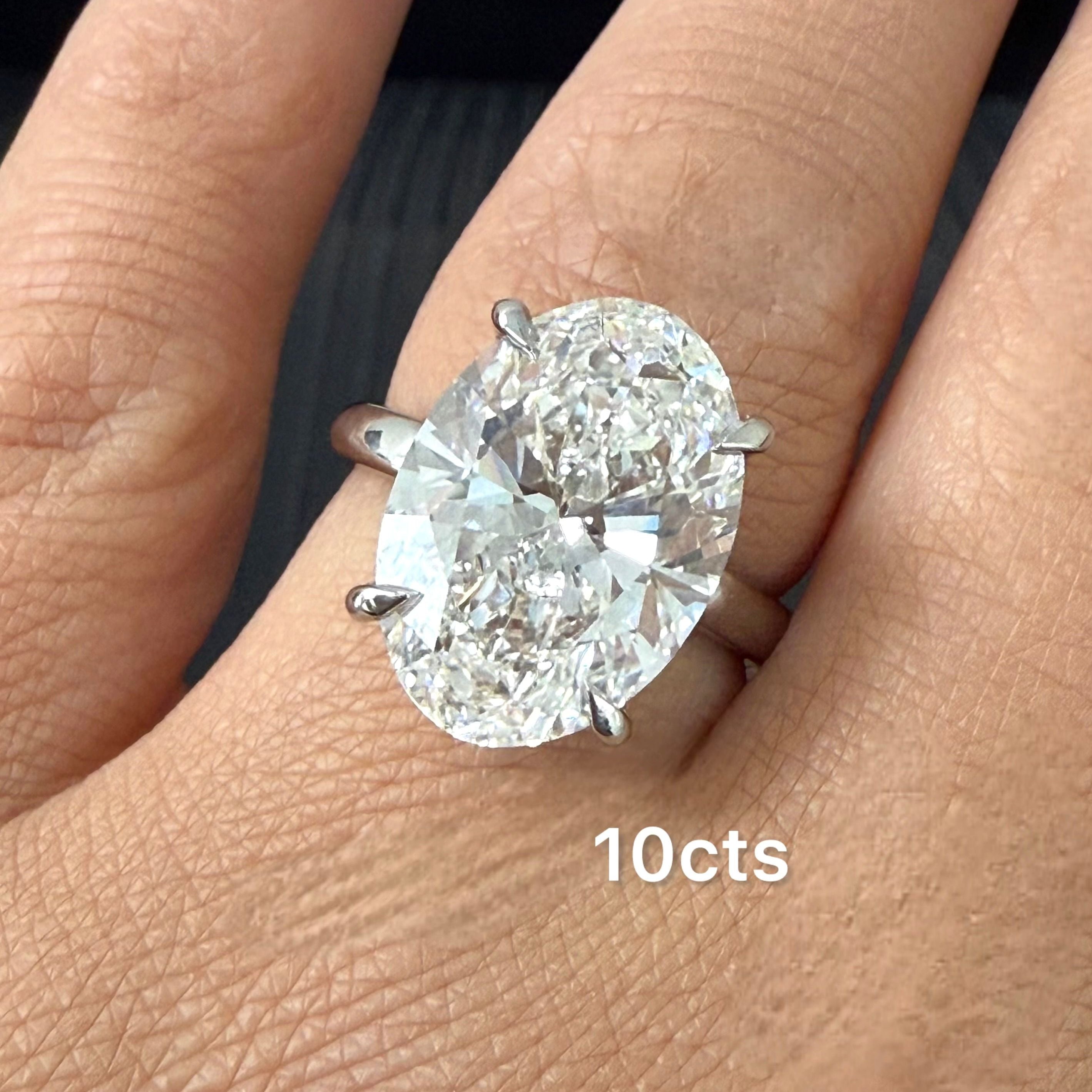 Diamond ring with '10cts' on a finger