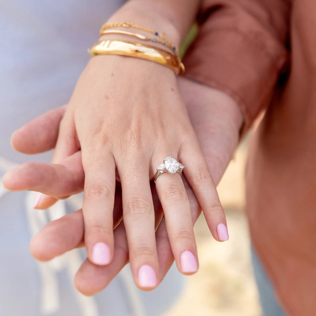 Customer photo: oval and pear three-stone engagement ring worn on hand in 18kt white gold