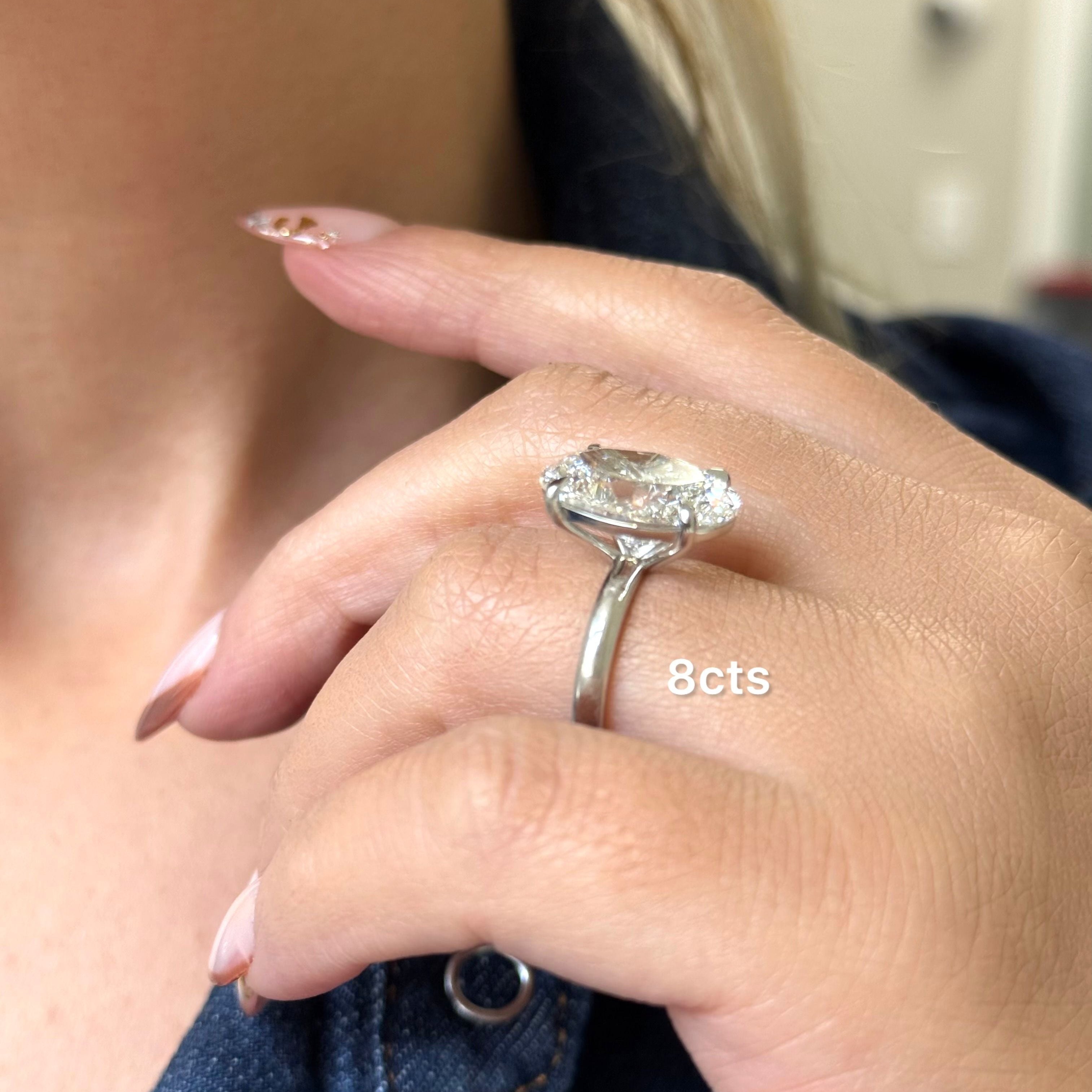 Close-up of a hand wearing a diamond ring with '8cts' text.
