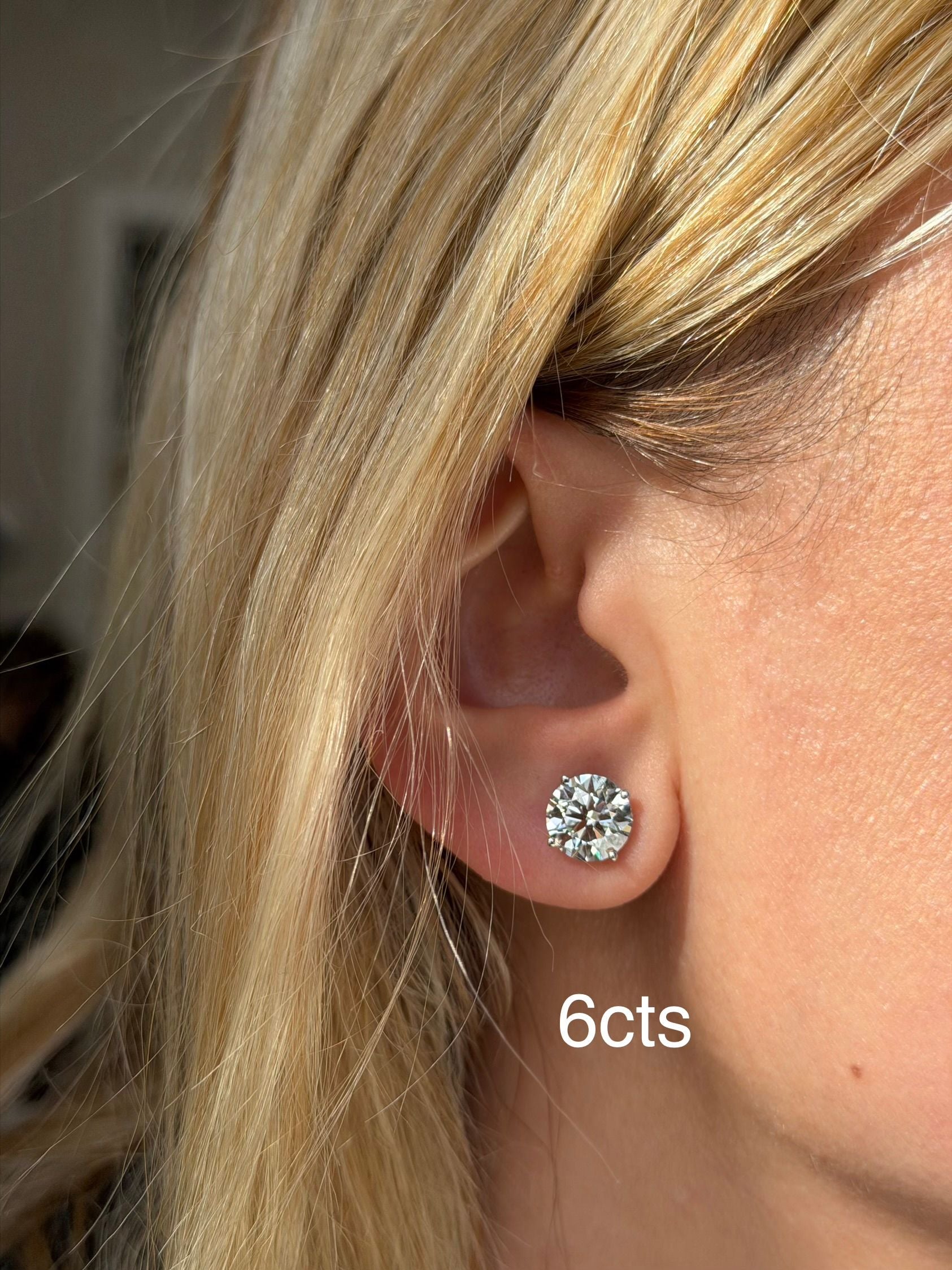 Close-up of an ear wearing a diamond earring with '6cts' text.