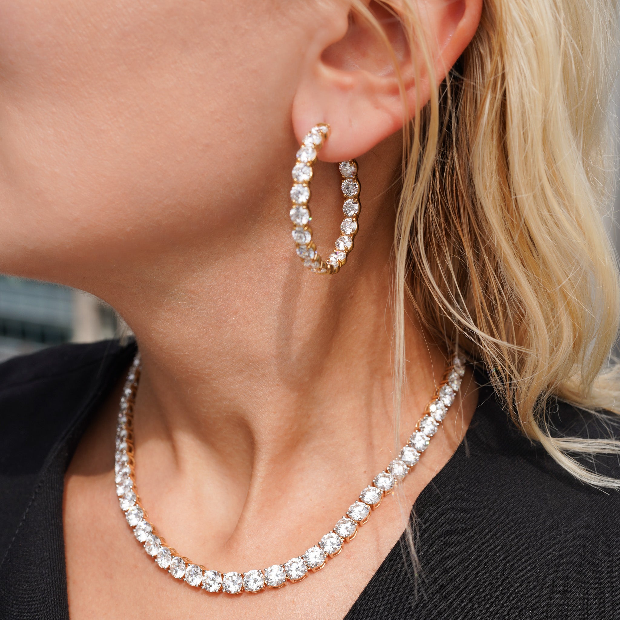 Close-up of a person wearing gold hoop earrings and a matching necklace.