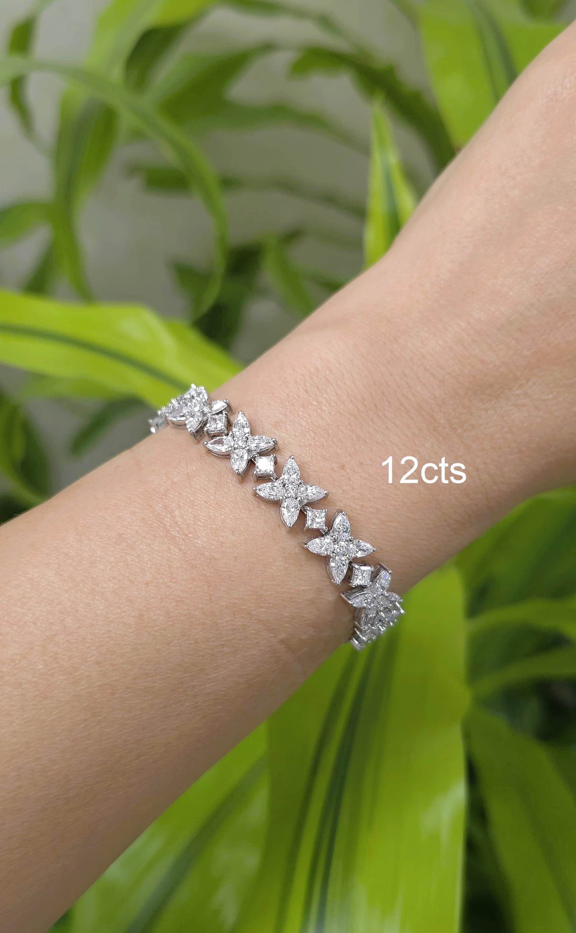 Silver bracelet with butterfly designs on a wrist against a green leafy background