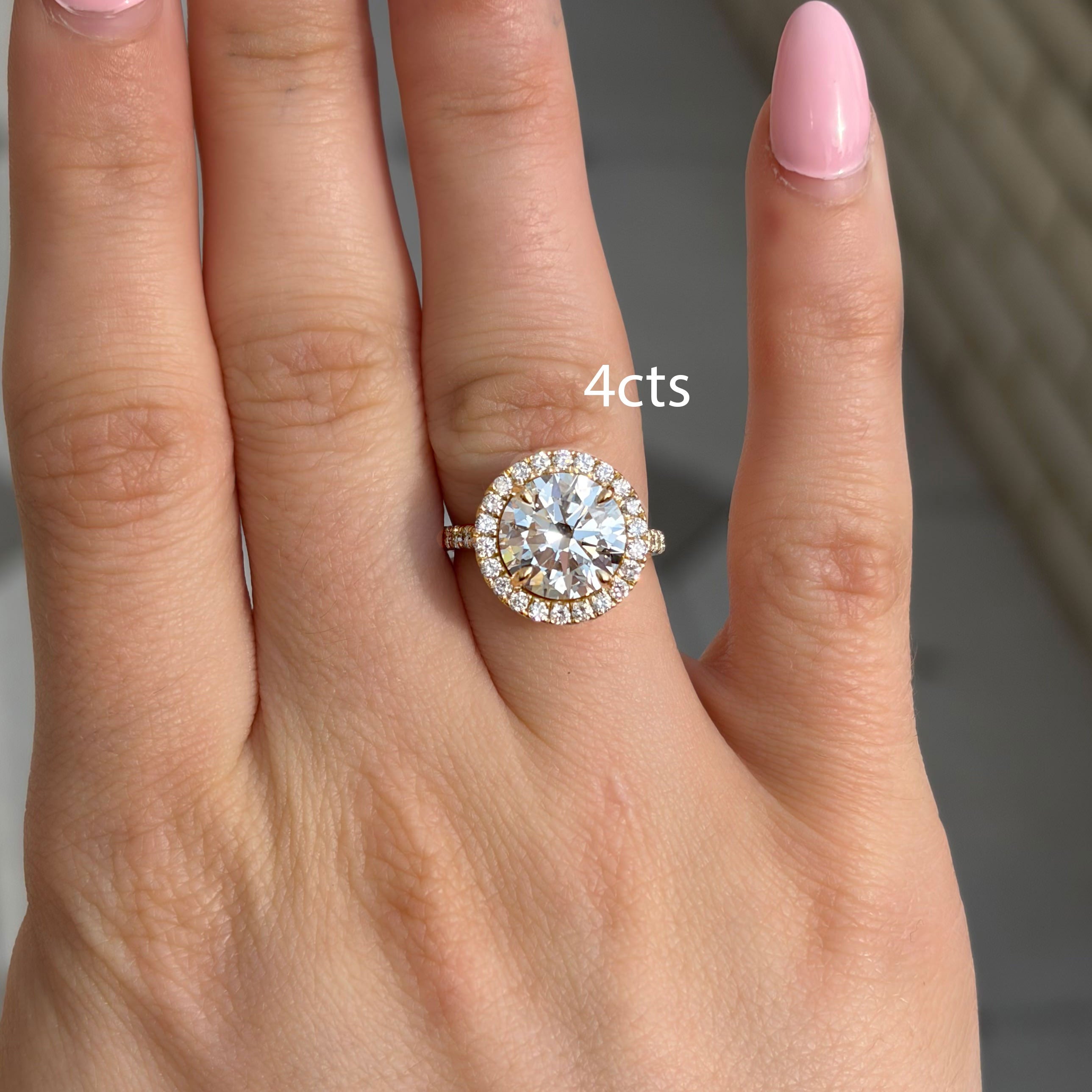 Hand wearing a diamond ring with '4 cts' text on a neutral background
