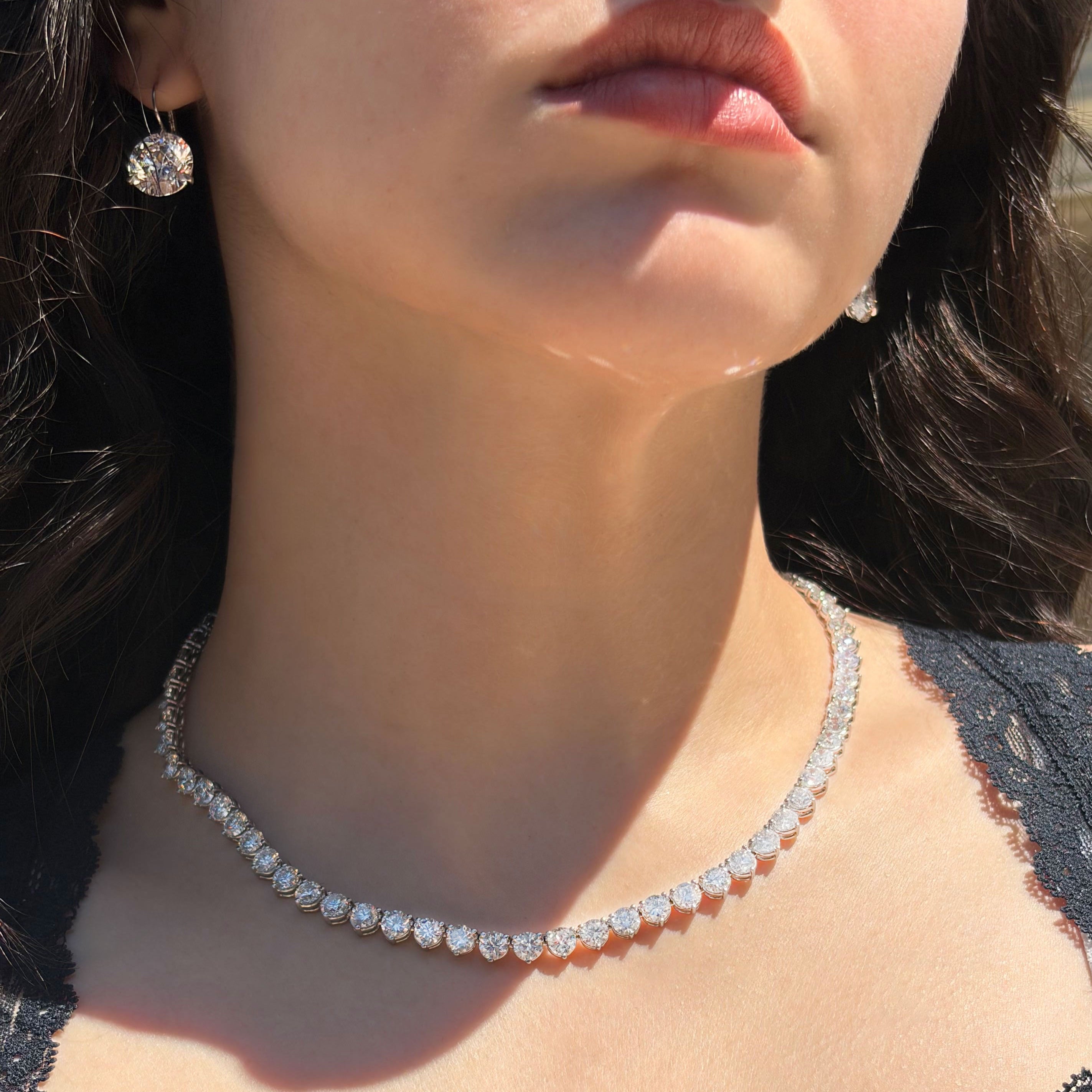 Close-up of a person wearing a diamond necklace with a blurred background