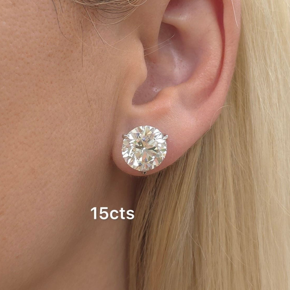 Close-up of a person wearing a diamond earring with '15cts' label.