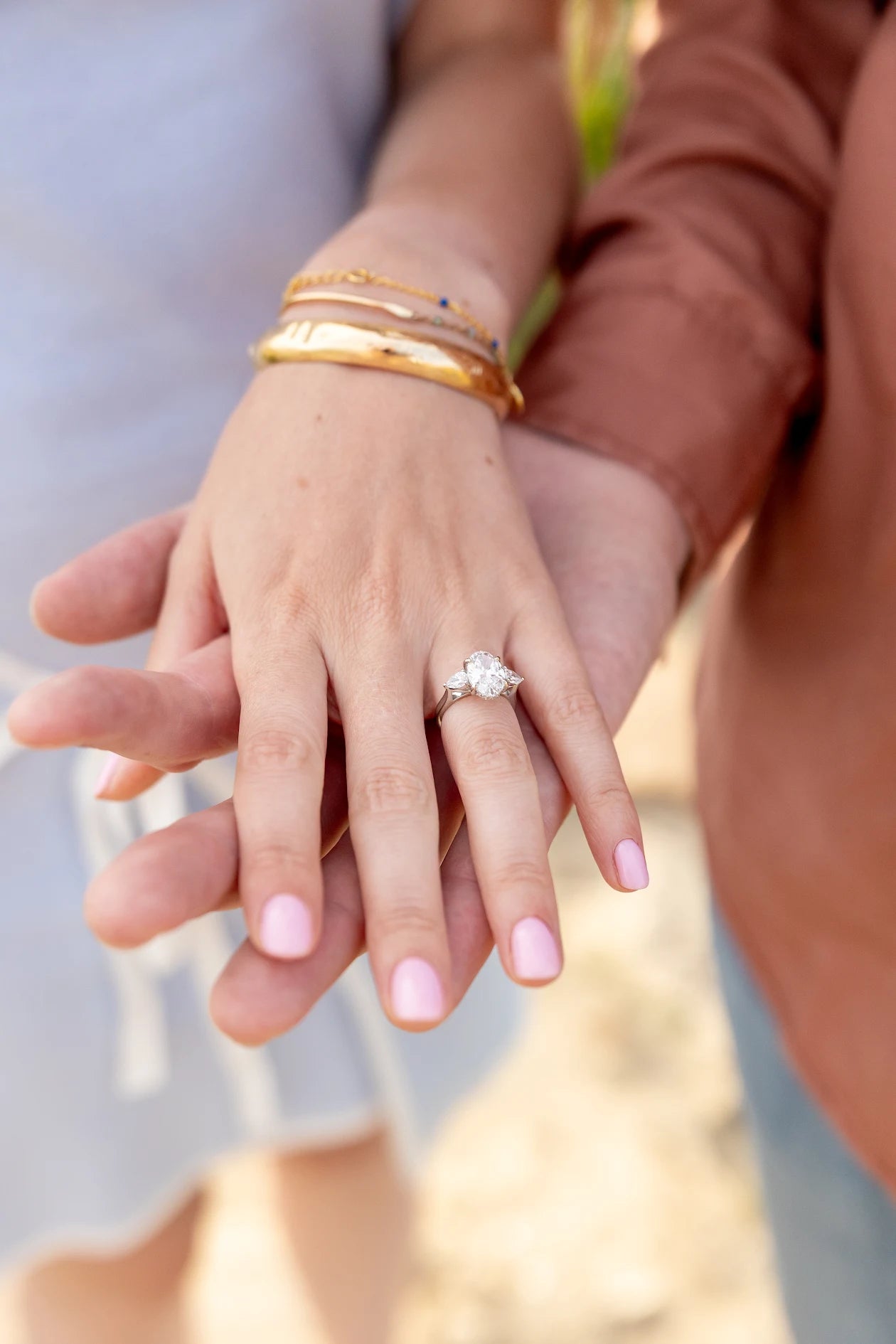 Customer photo: oval and pear three-stone engagement ring worn on hand in 18kt white gold