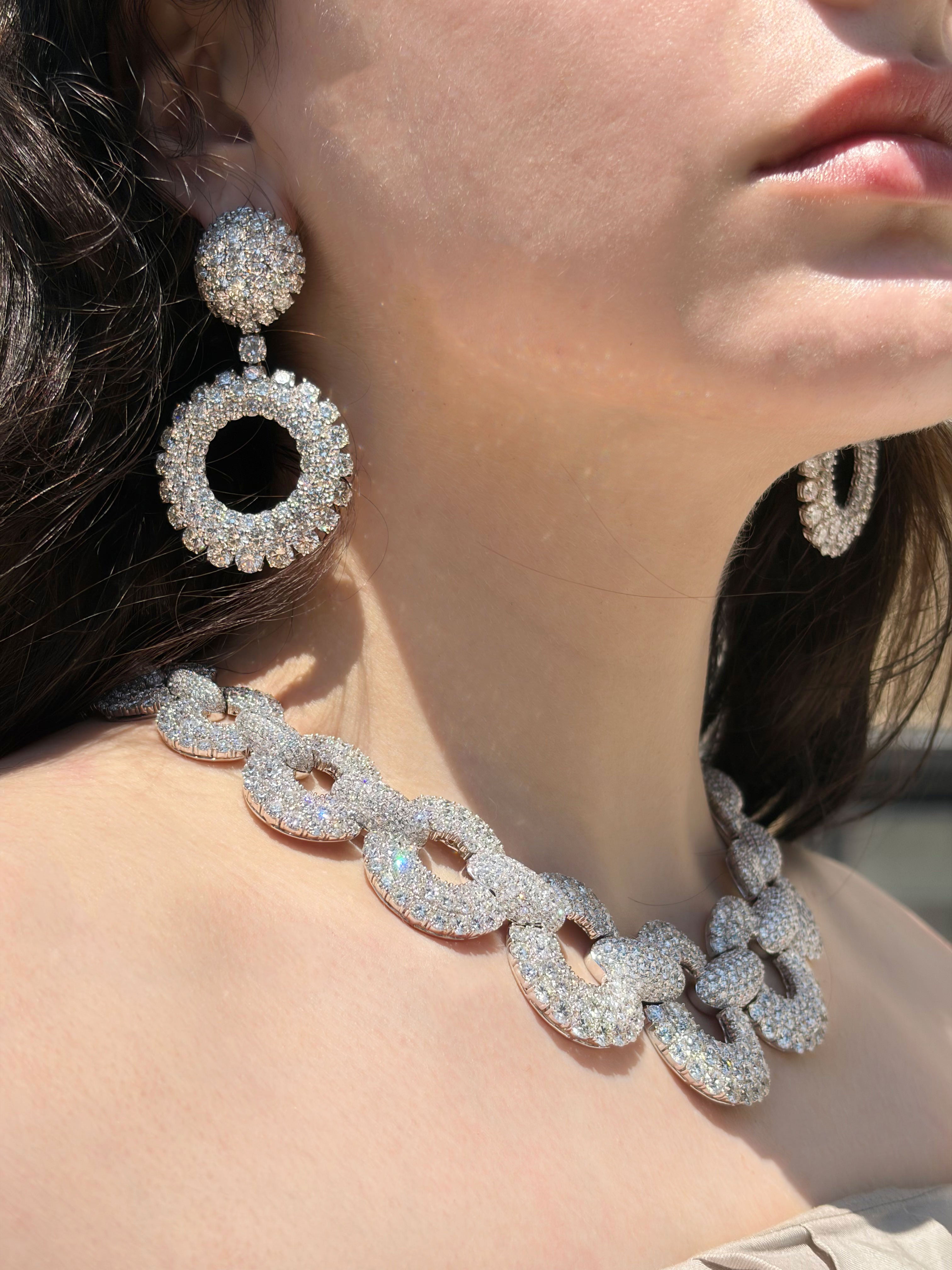 Close-up of a person wearing sparkling diamond earrings and necklace.