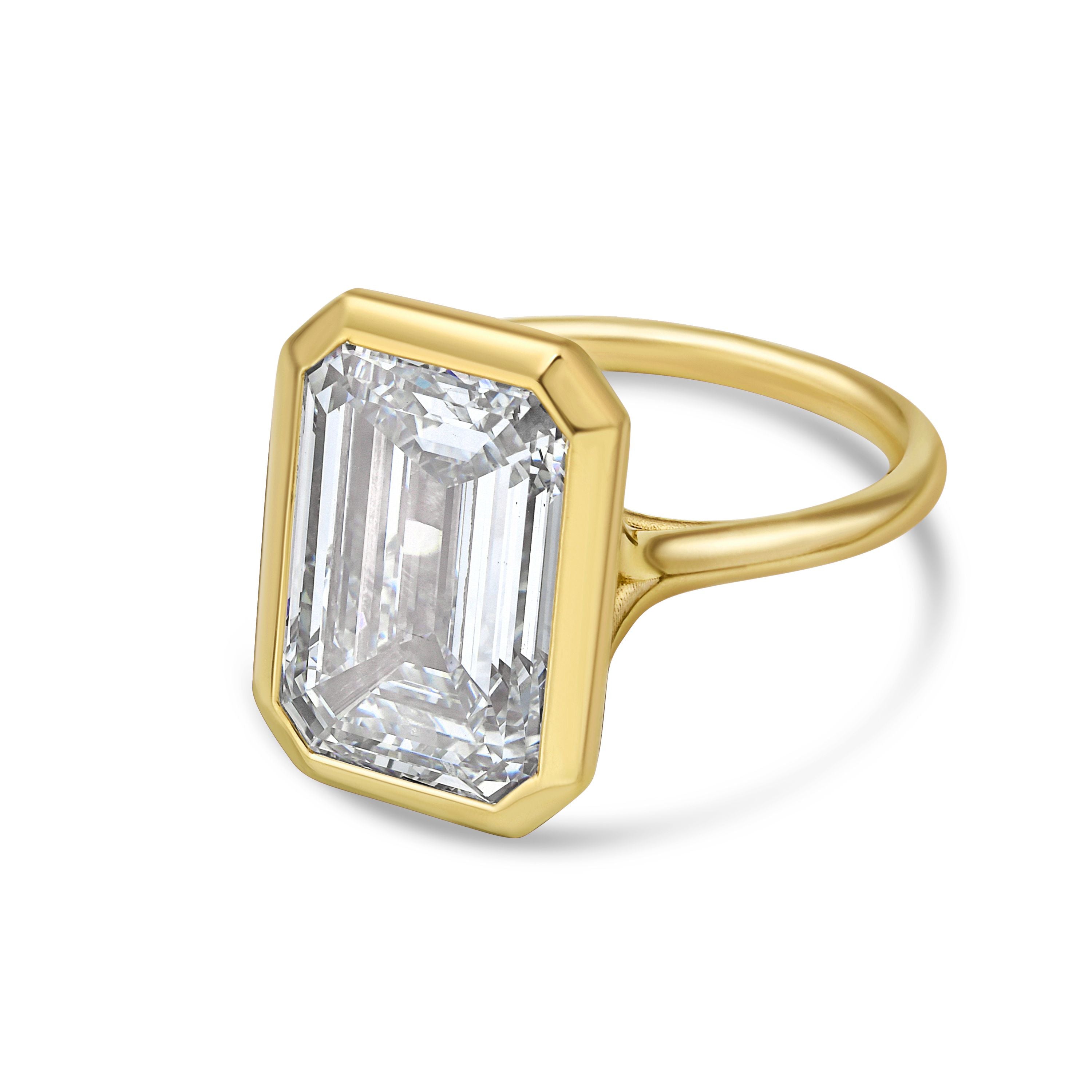 Gold ring with a large emerald-cut diamond on a white background