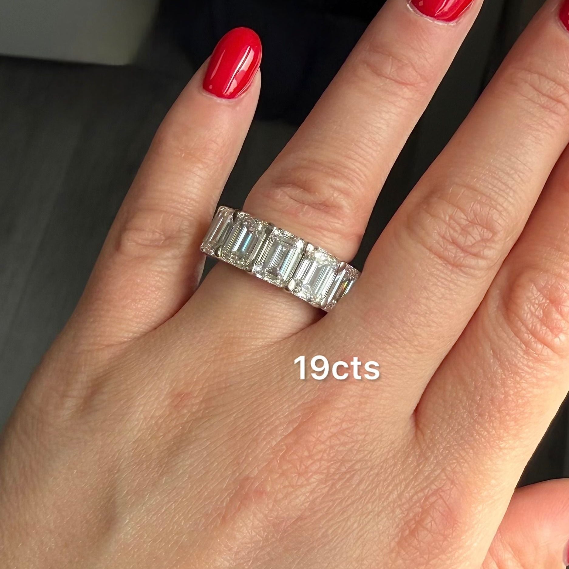 Hand with red nail polish wearing a silver ring, with '19cts' text.