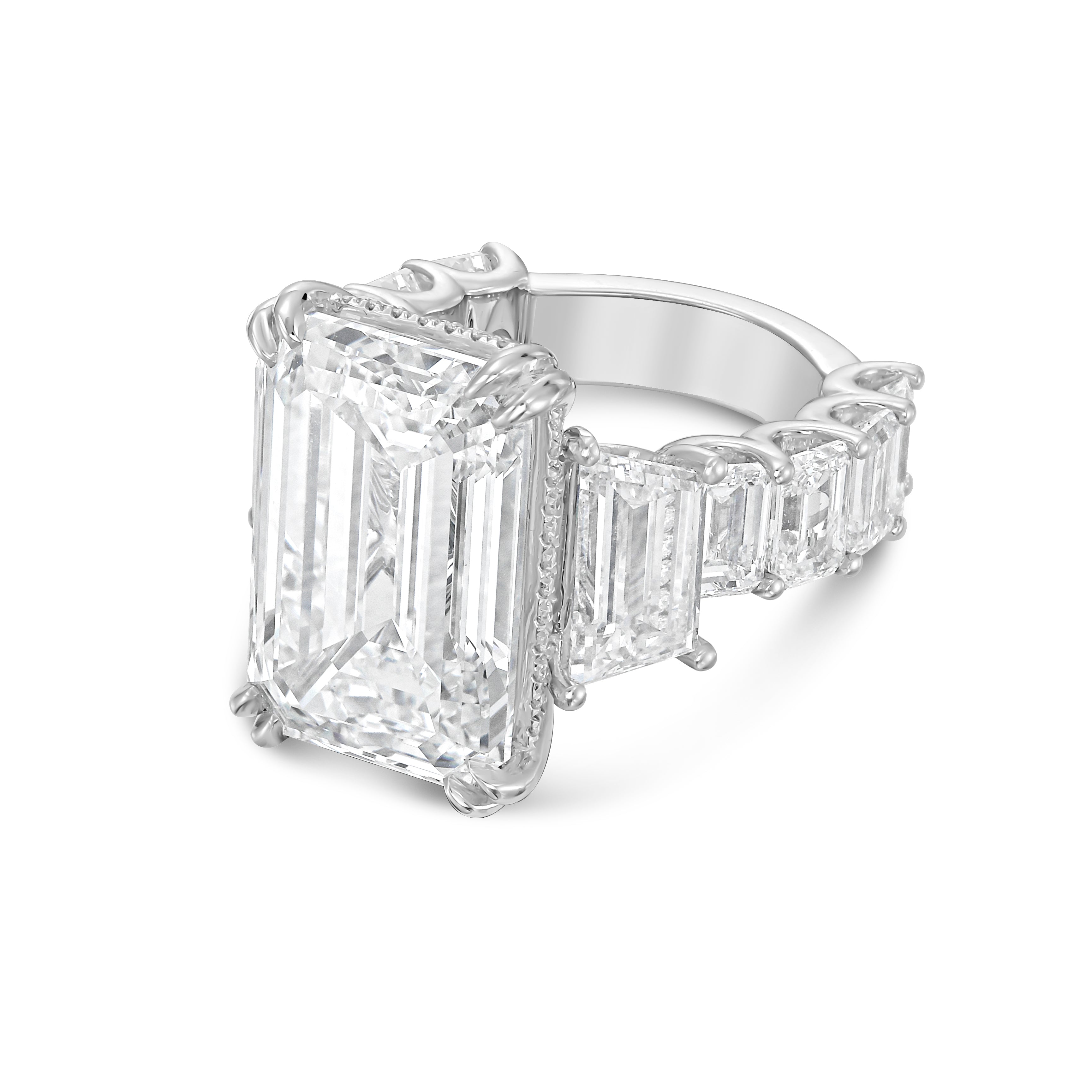 Side profile of 18k white gold emerald cut diamond ring showing trapezoid stones and emerald accents